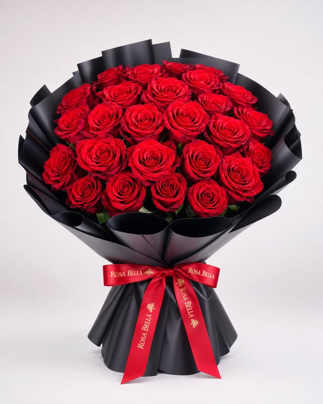 A tall bouquet of deep red roses in black wrapping paper with a red satin ribbon.