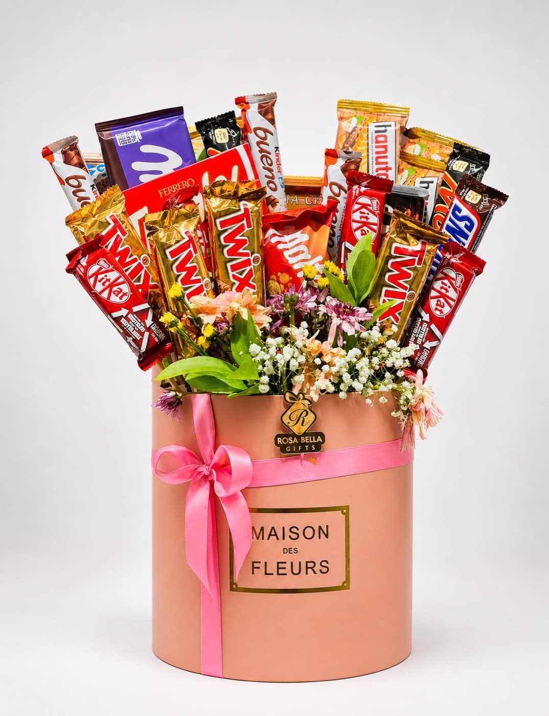 A round gift box holding assorted chocolate bars arranged upright with fresh flowers between them.